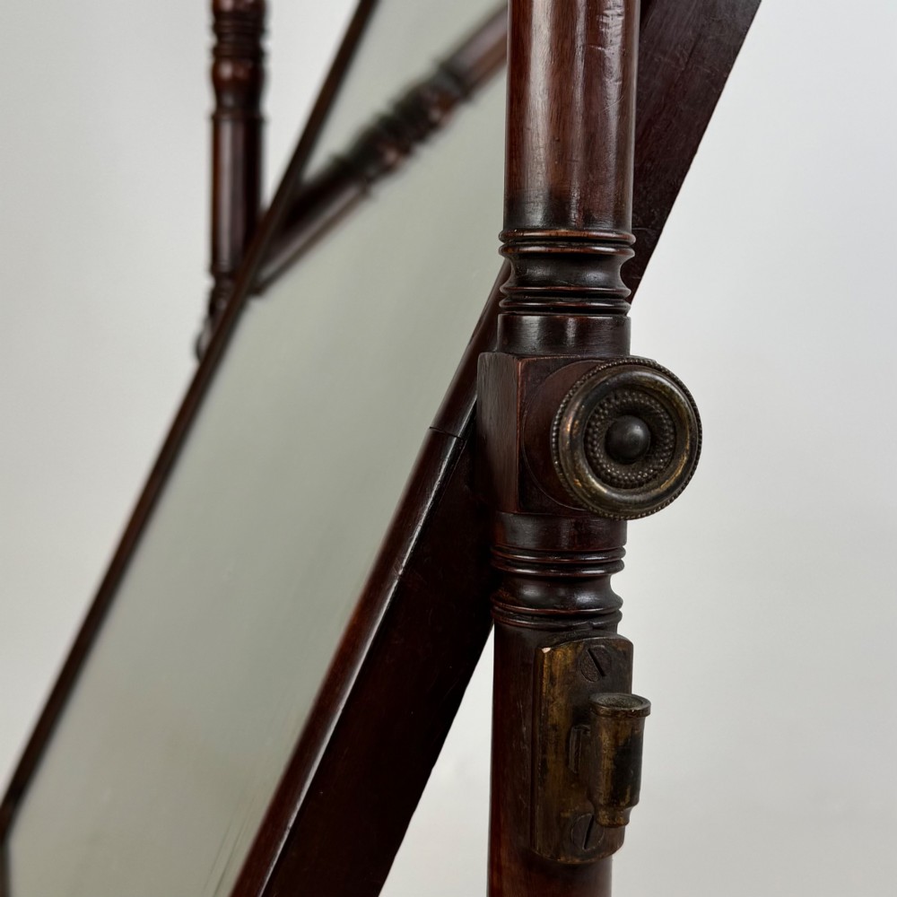 A 19th-century mahogany dressing mirror with turned side columns, carved scrollwork cresting, and an adjustable rectangular glass frame on a shaped base. View XIII