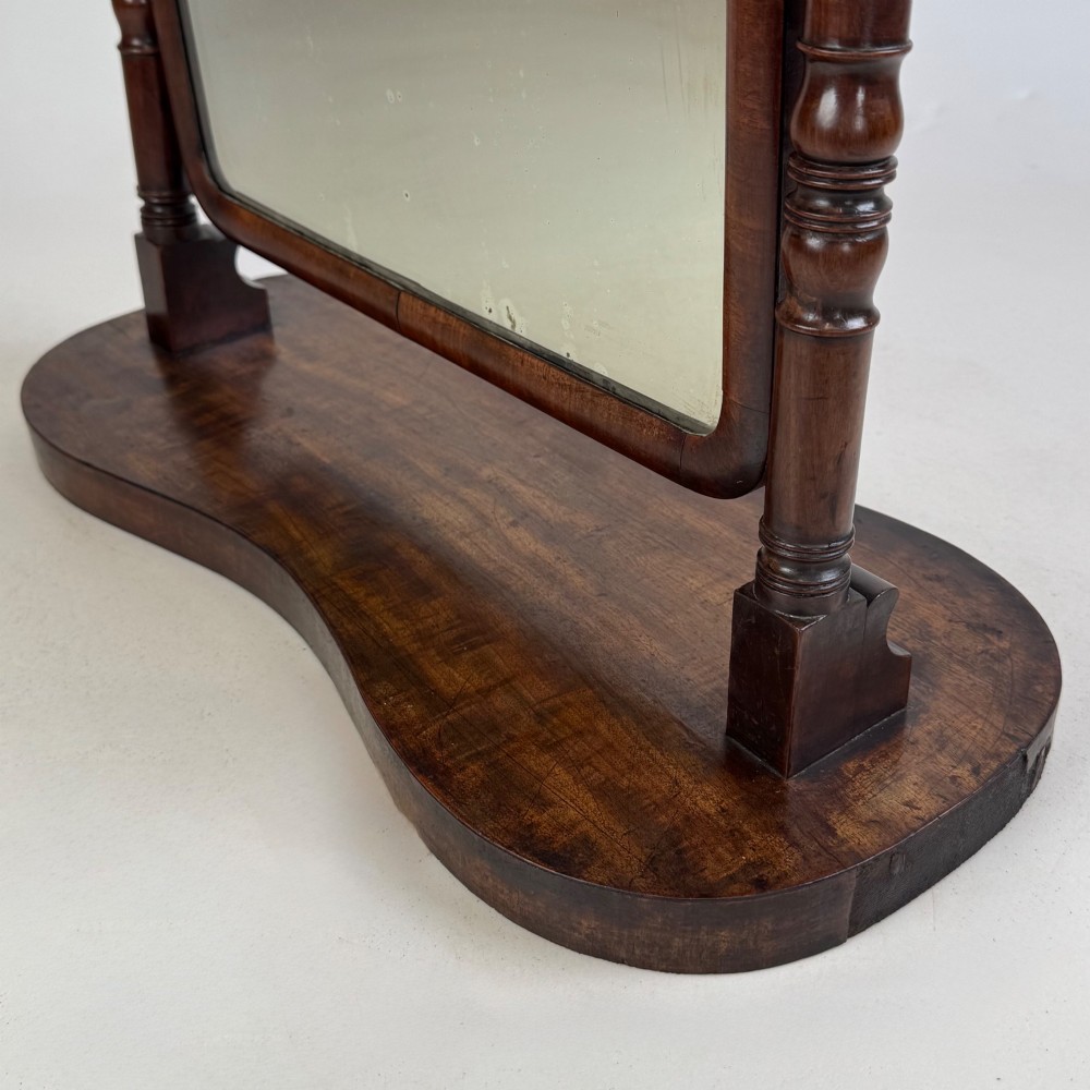 A 19th-century mahogany dressing mirror with turned side columns, carved scrollwork cresting, and an adjustable rectangular glass frame on a shaped base. View XIV