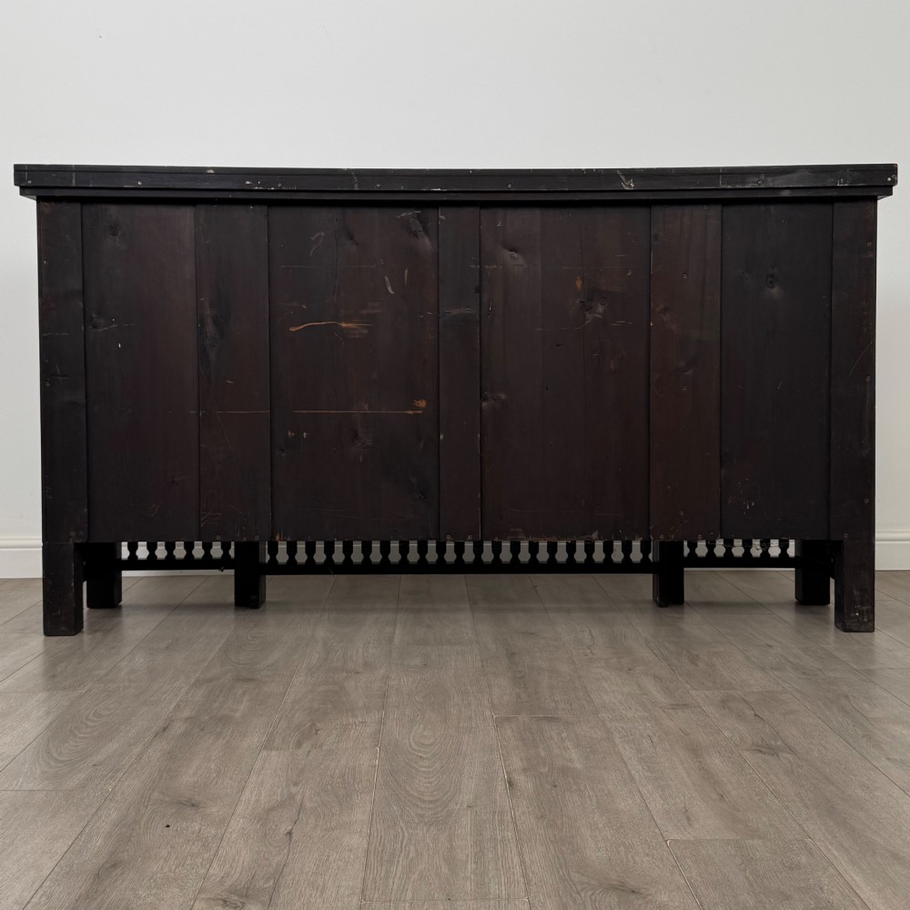 An antique ebonised black wood sideboard featuring a central open bookshelf, two carved side doors with glass panels, brass hardware, and a spindled lower rail. View VII
