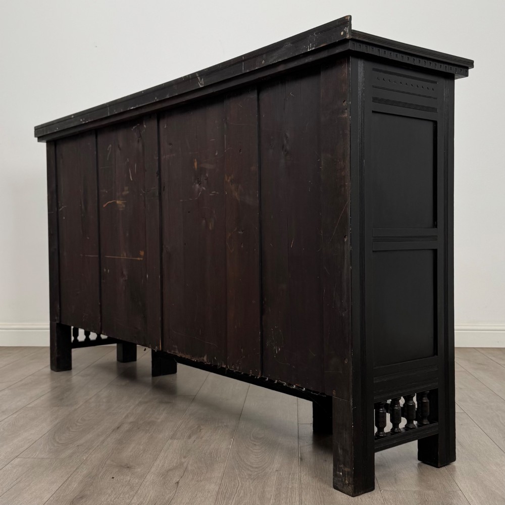 An antique ebonised black wood sideboard featuring a central open bookshelf, two carved side doors with glass panels, brass hardware, and a spindled lower rail. View VIII