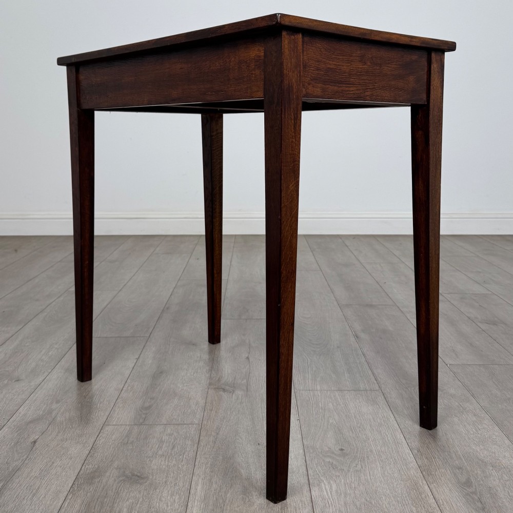 An antique dark oak Edwardian side table with two front drawers, metallic drop handles, and straight tapered legs. View VI