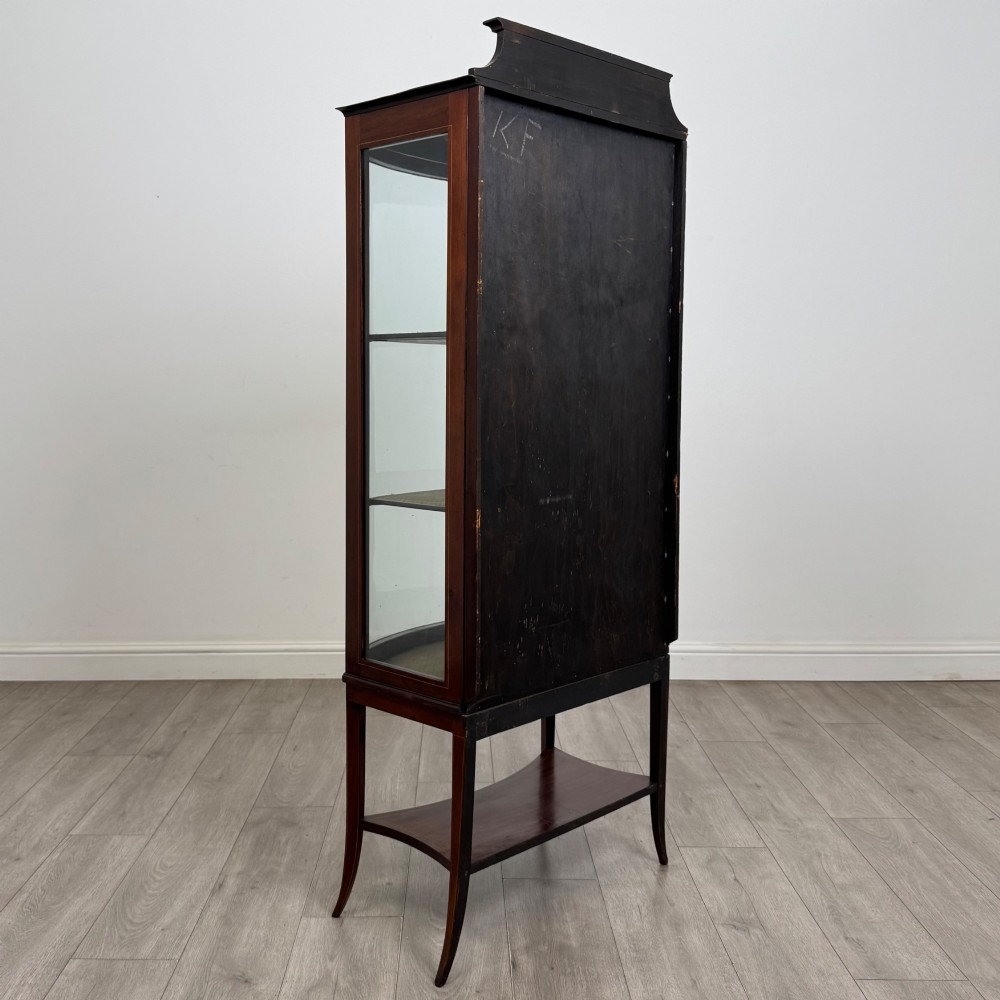 An Edwardian mahogany display cabinet with a bow-front glazed door, fabric-lined interior shelves, marquetry inlay, and slender tapered legs with a lower shelf. View V