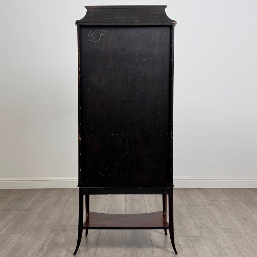 An Edwardian mahogany display cabinet with a bow-front glazed door, fabric-lined interior shelves, marquetry inlay, and slender tapered legs with a lower shelf. View VI