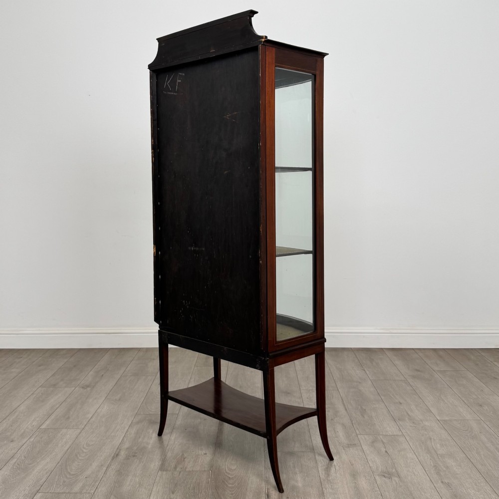 An Edwardian mahogany display cabinet with a bow-front glazed door, fabric-lined interior shelves, marquetry inlay, and slender tapered legs with a lower shelf. View VII