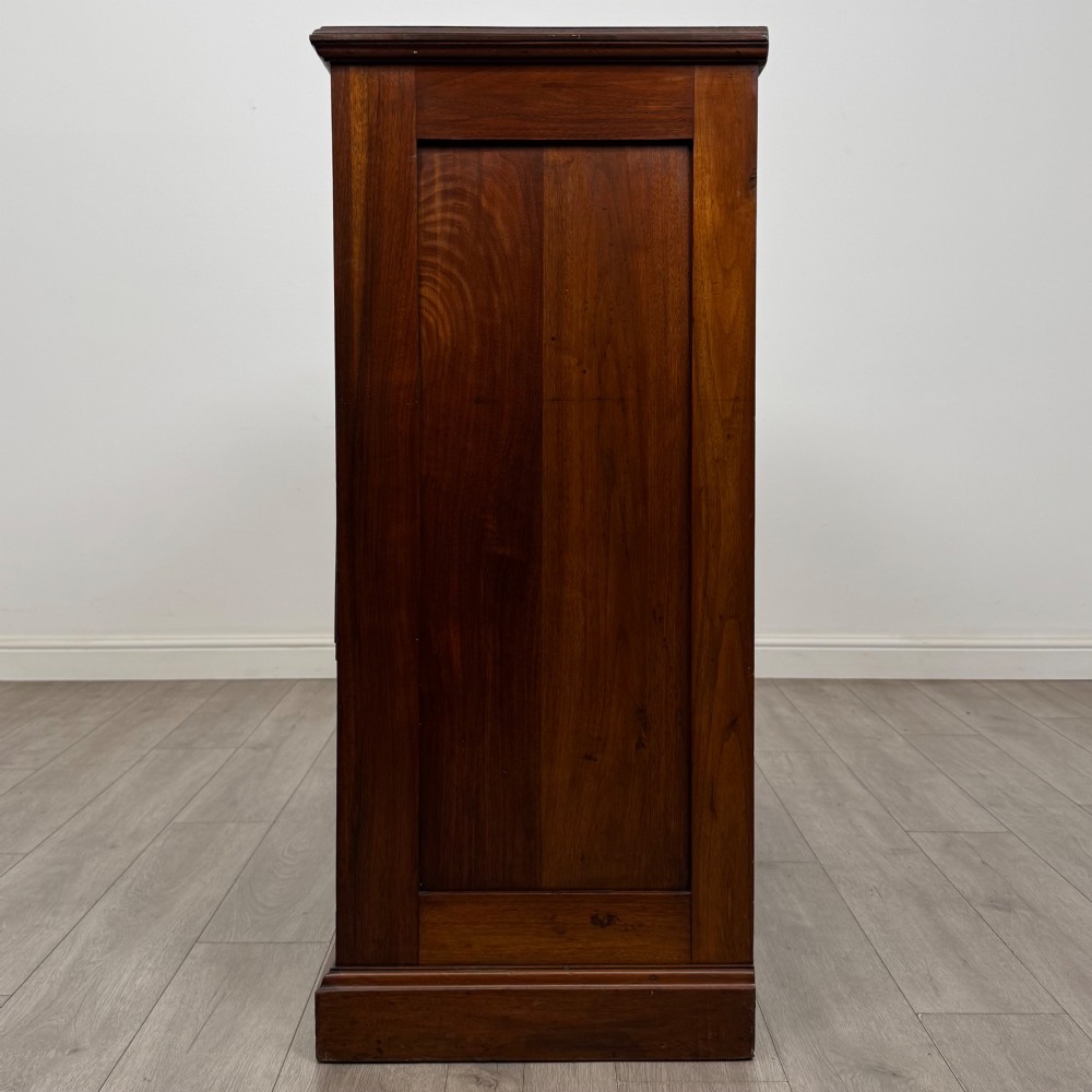An Edwardian walnut chest of drawers featuring a two over three drawer layout with brass drop handles and a solid plinth base. View III