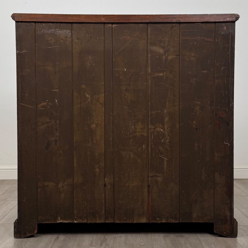 An Edwardian walnut chest of drawers featuring a two over three drawer layout with brass drop handles and a solid plinth base. View V