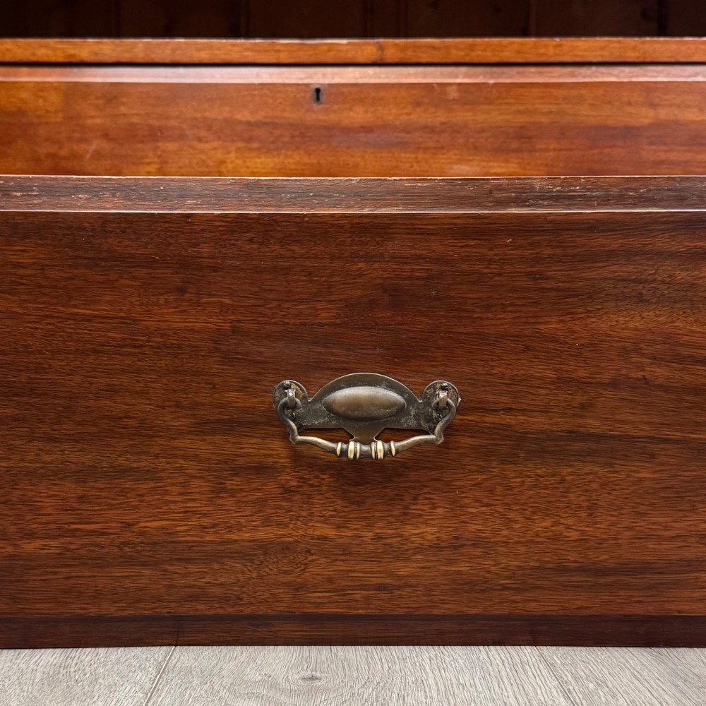 An Edwardian walnut chest of drawers featuring a two over three drawer layout with brass drop handles and a solid plinth base. View XI