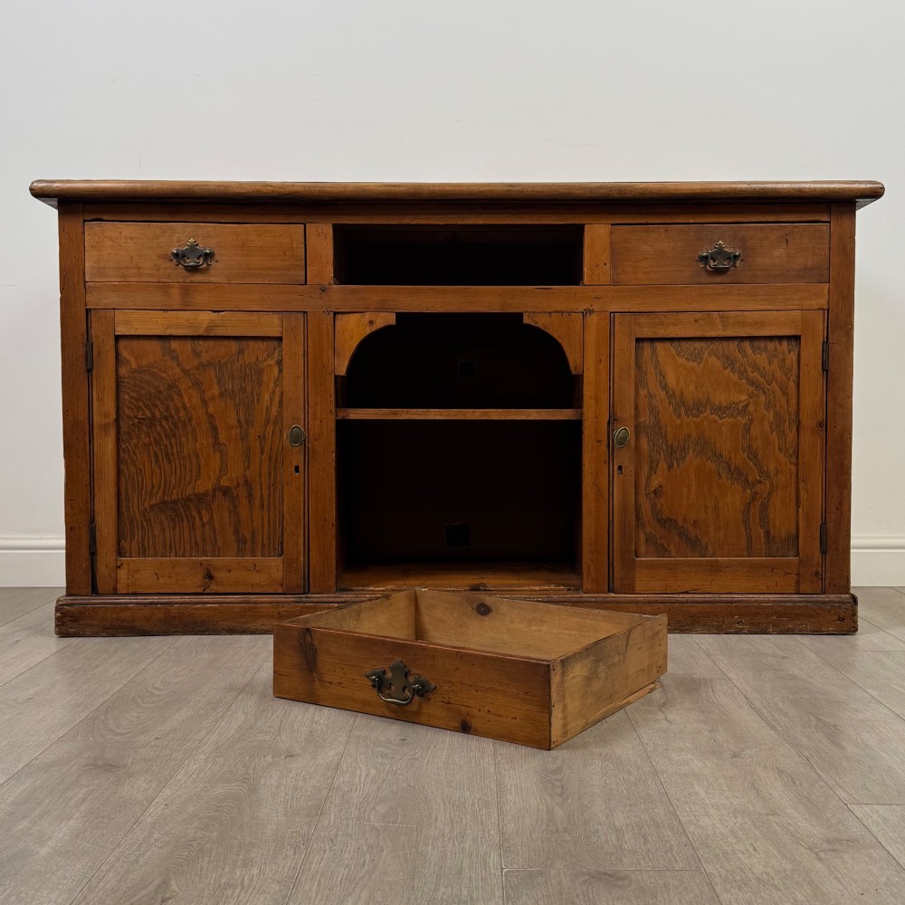 A 19th-century pine farmhouse dresser base featuring three upper drawers above two cupboard doors and an open central shelf. View XI