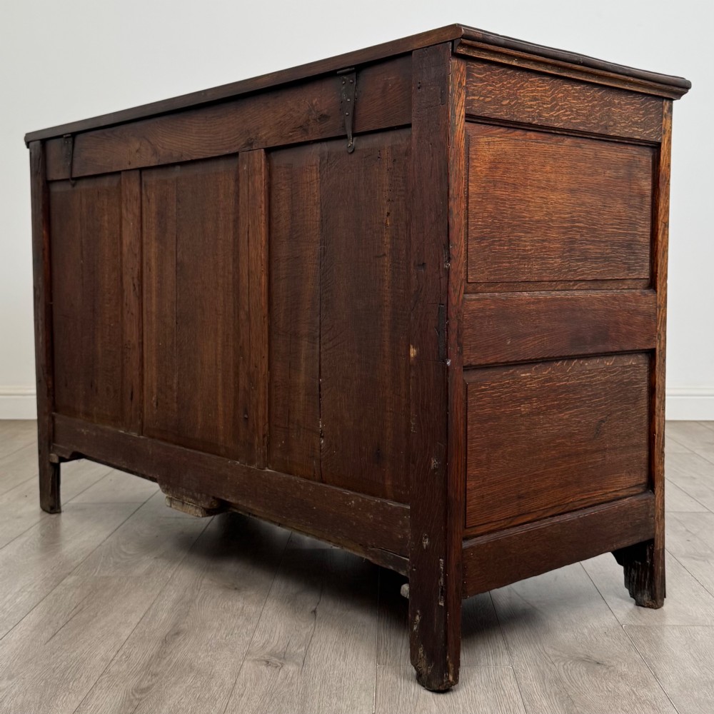 An 18th-century Georgian oak mule chest featuring four arched fielded panels, two base drawers with brass hardware, and a shaped apron. View VI
