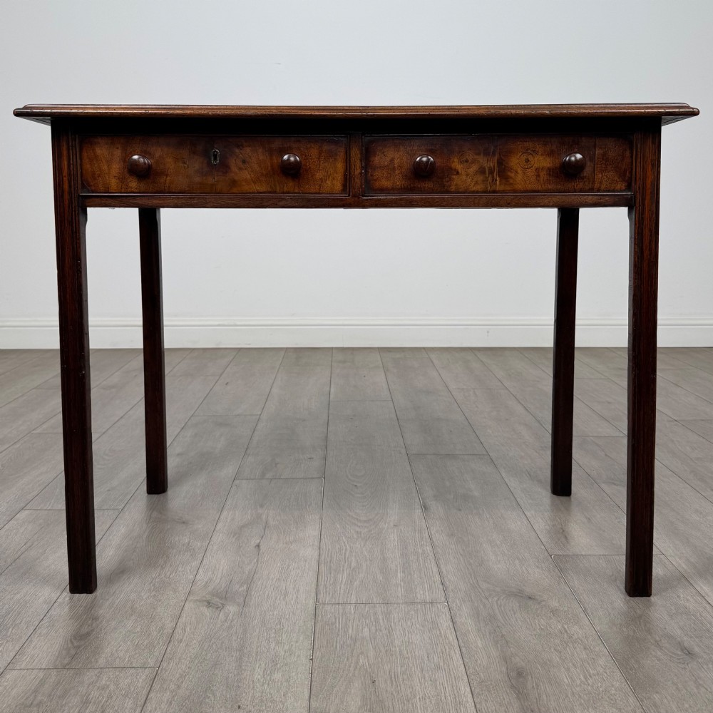 A dark mahogany Georgian style writing table featuring two frieze drawers with turned wood knobs and straight legs.