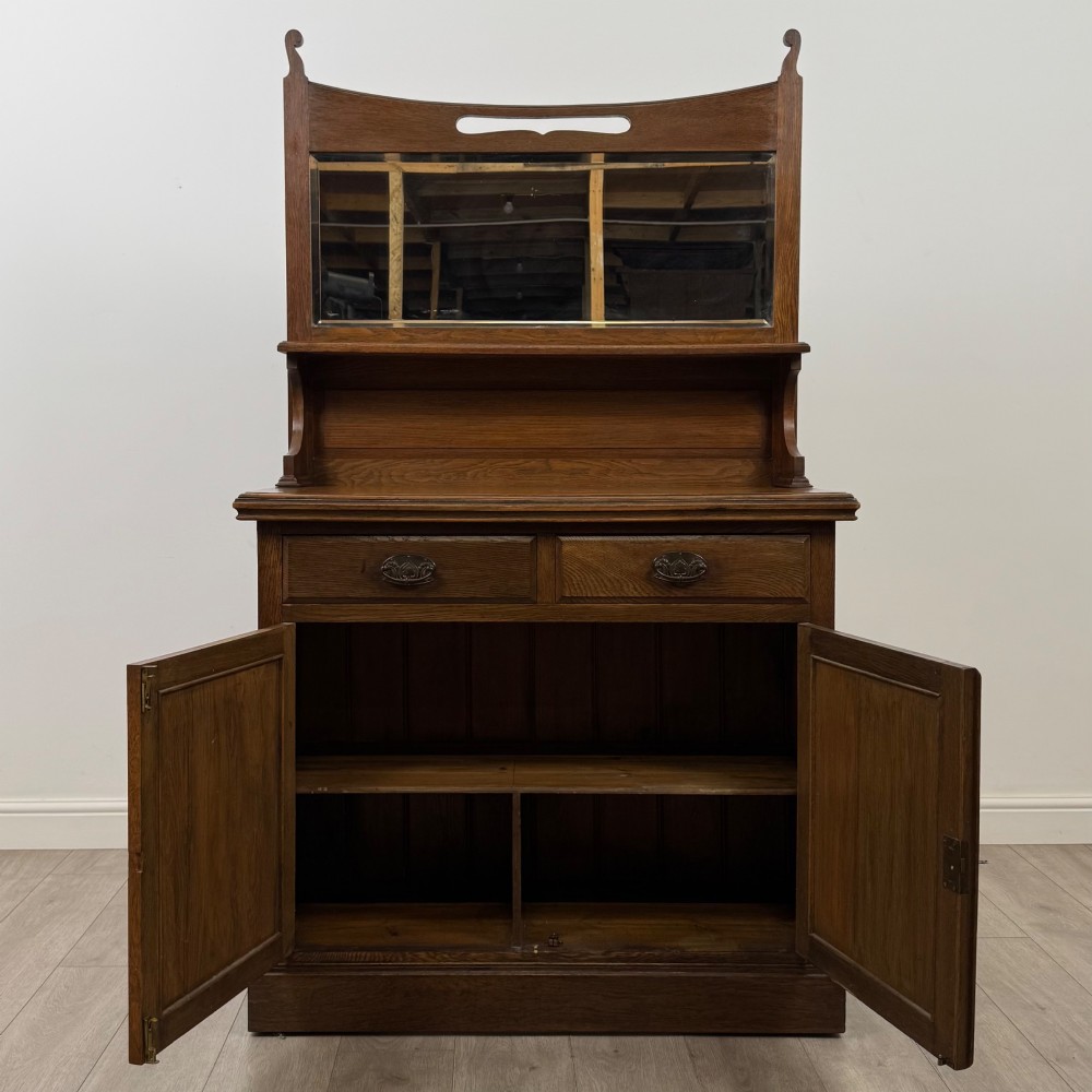 An early 20th-century warm brown oak mirror back sideboard featuring two drawers, a double-door cupboard base, and an elevated mirror plate cresting. View II