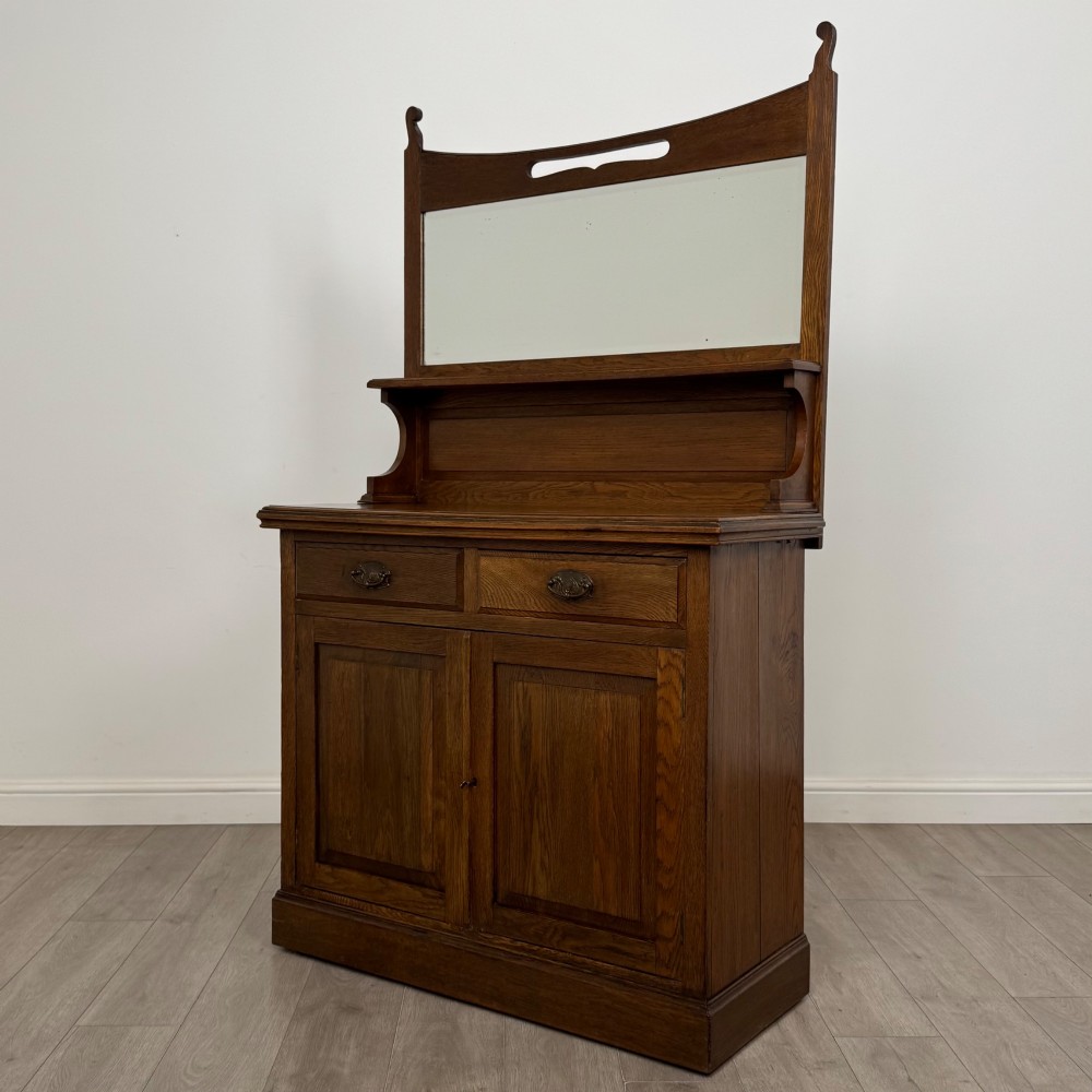 An early 20th-century warm brown oak mirror back sideboard featuring two drawers, a double-door cupboard base, and an elevated mirror plate cresting. View III