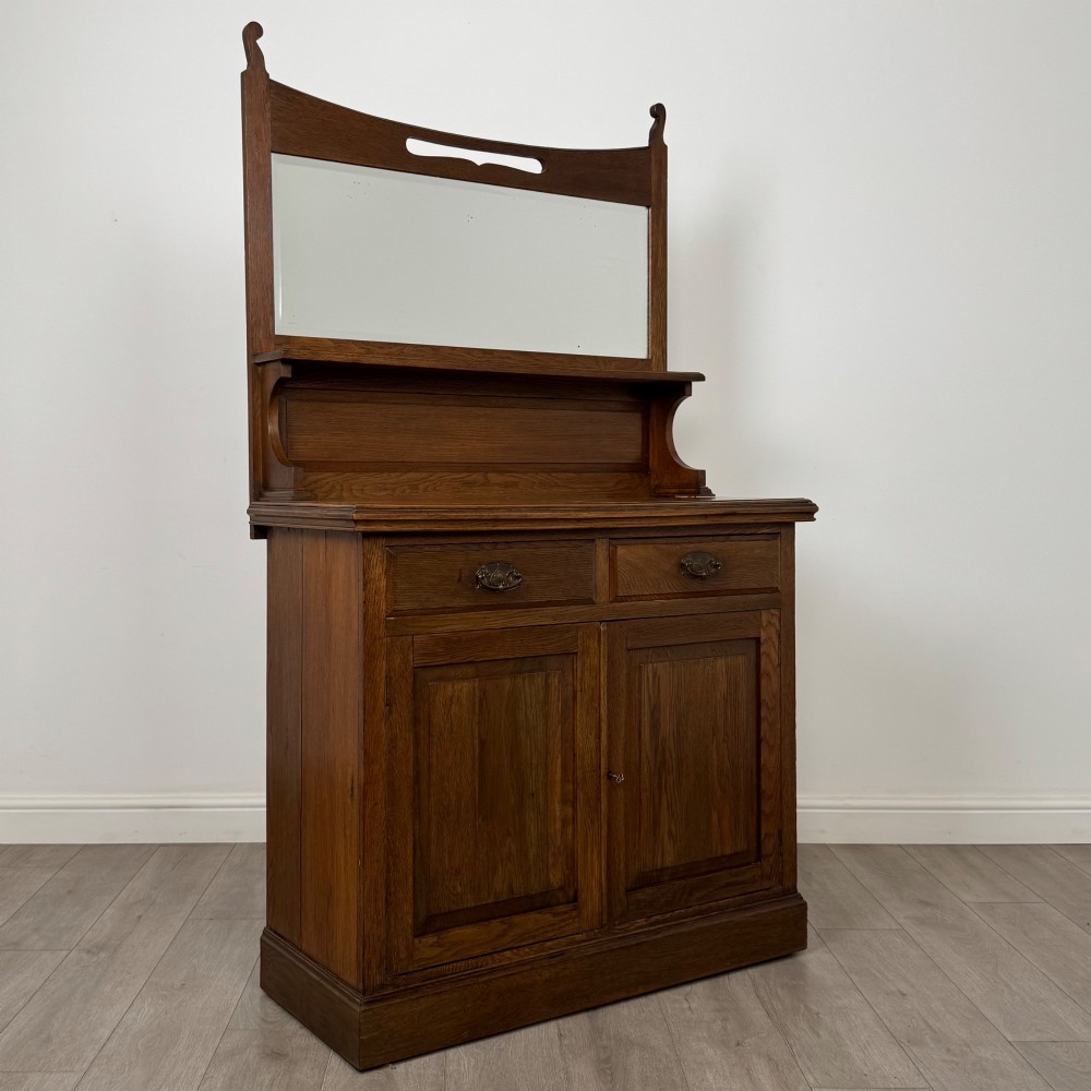 An early 20th-century warm brown oak mirror back sideboard featuring two drawers, a double-door cupboard base, and an elevated mirror plate cresting. View IX