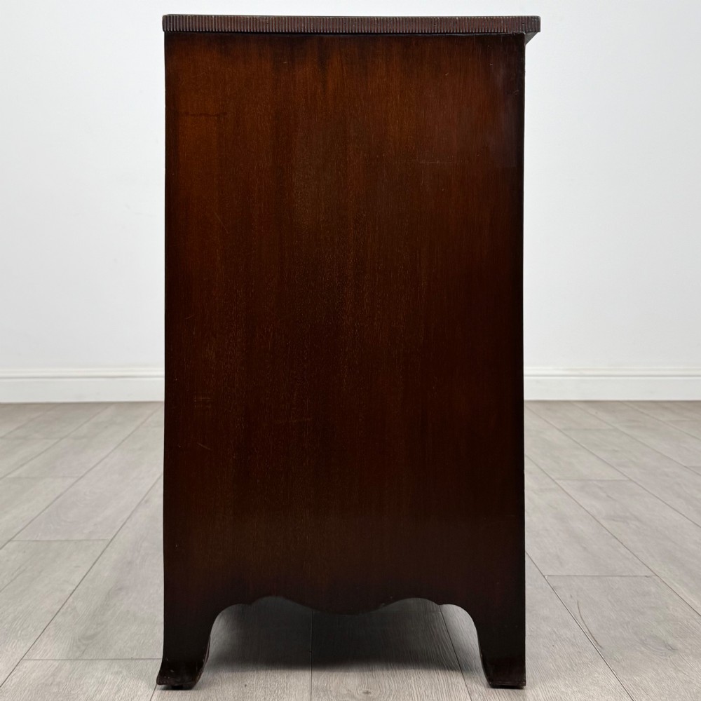 A mahogany serpentine chest of drawers featuring four graduating drawer tiers with brass handles and a curved front profile. View III