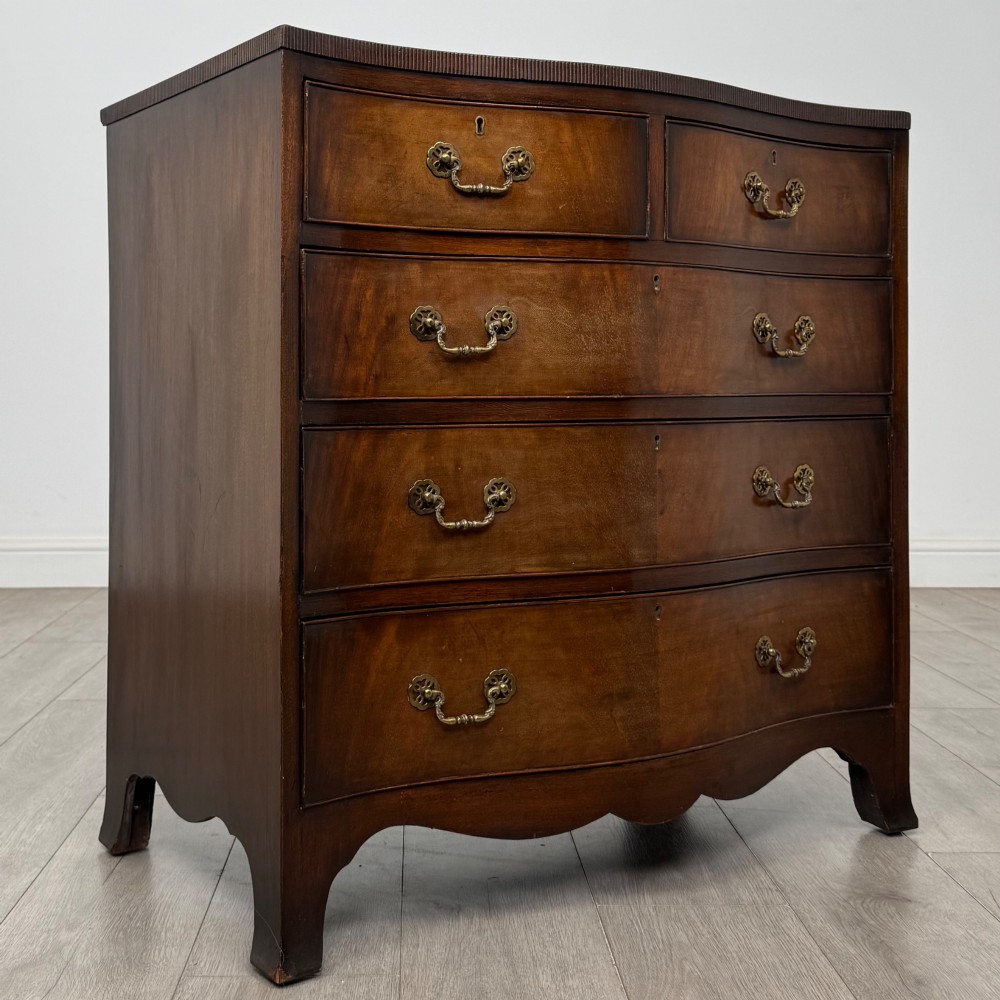 A mahogany serpentine chest of drawers featuring four graduating drawer tiers with brass handles and a curved front profile. View VIII