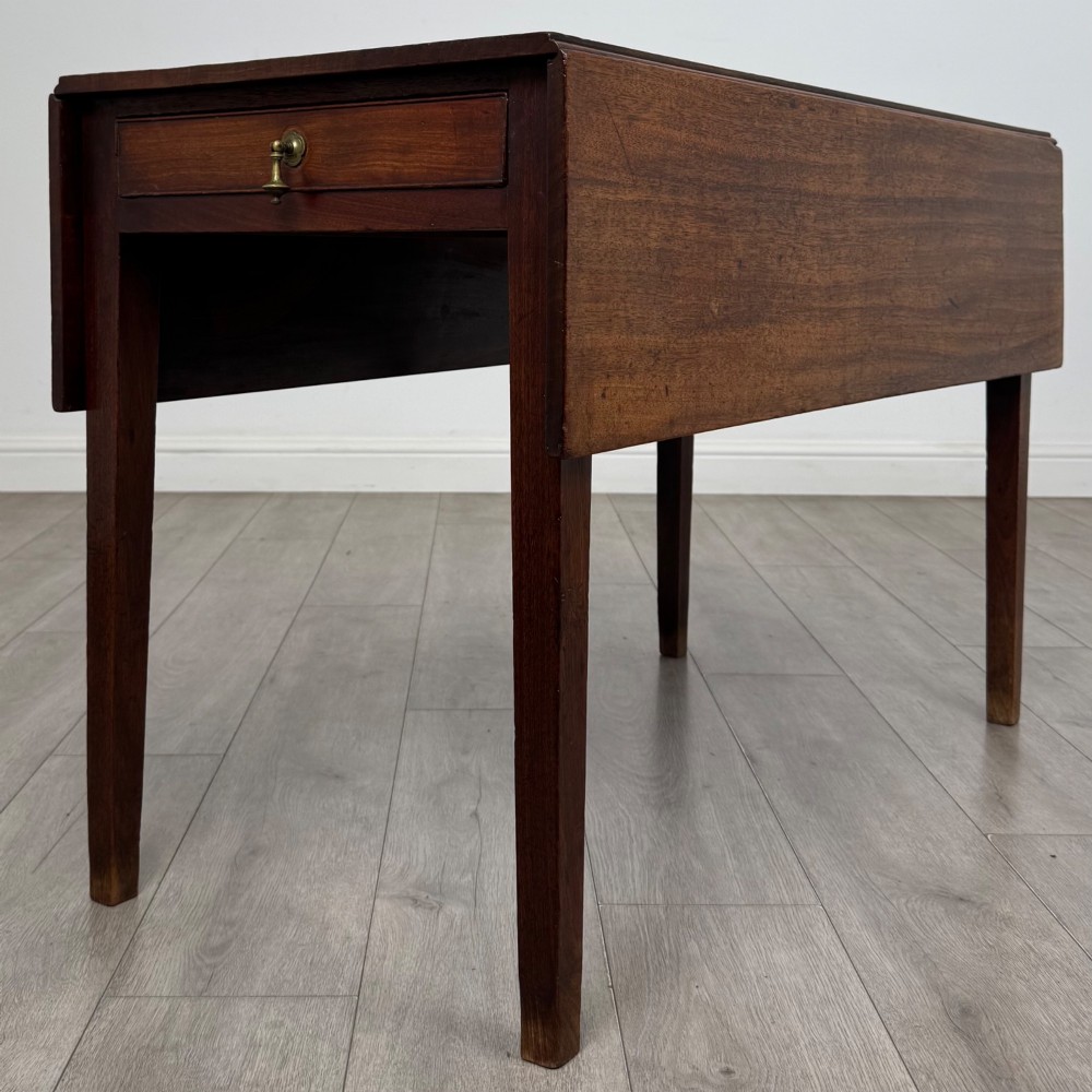 A 19th-century Georgian style dark mahogany Pembroke side table with drop leaves, tapered square legs, and a single frieze drawer with a brass drop handle.
