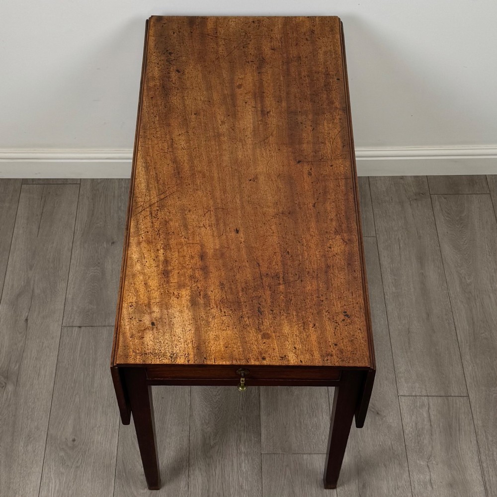 A 19th-century Georgian style dark mahogany Pembroke side table with drop leaves, tapered square legs, and a single frieze drawer with a brass drop handle. View X
