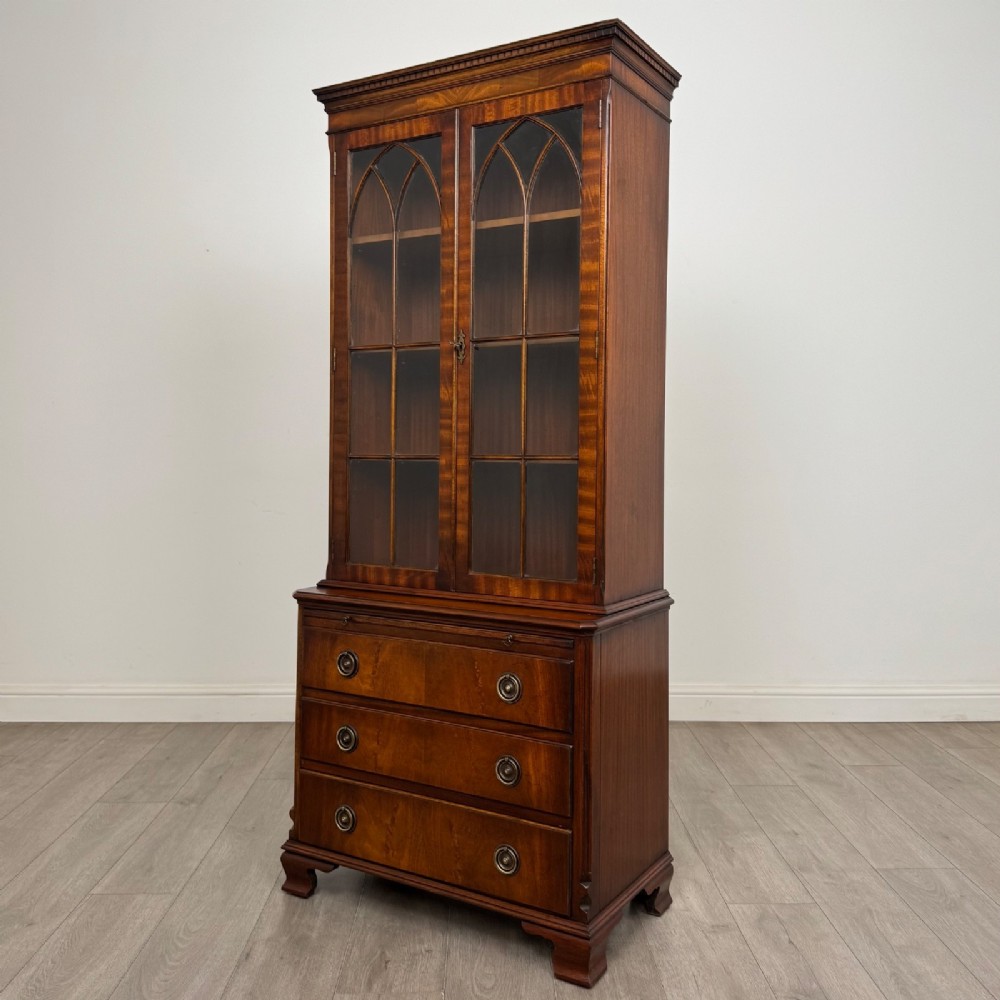A tall Georgian style mahogany bookcase featuring two glazed doors with gothic arch tracery above a lower section with three drawers. View IV