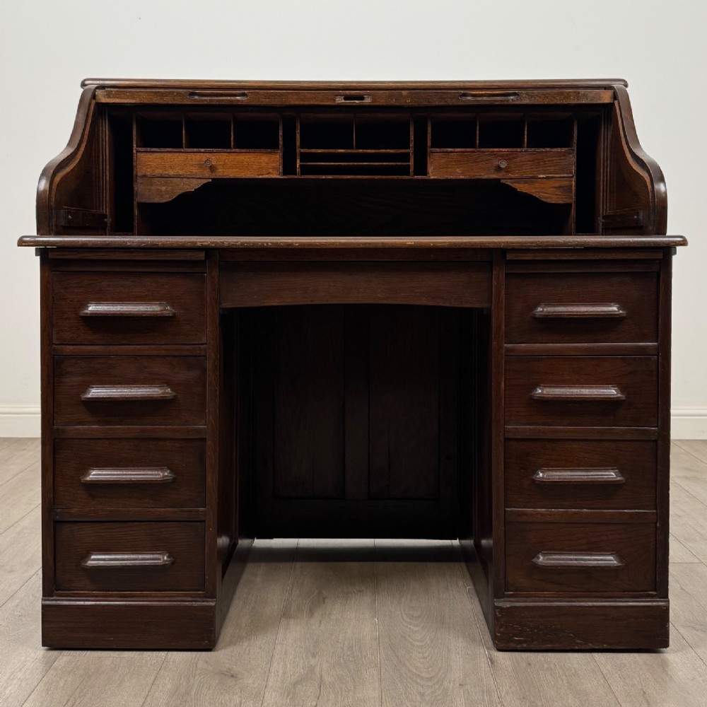 An Edwardian dark oak roll top desk featuring a slatted tambour front above a twin pedestal base with eight drawers. View II