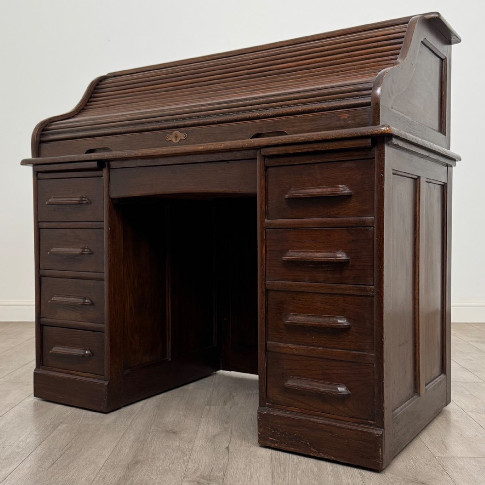 An Edwardian dark oak roll top desk featuring a slatted tambour front above a twin pedestal base with eight drawers. View III
