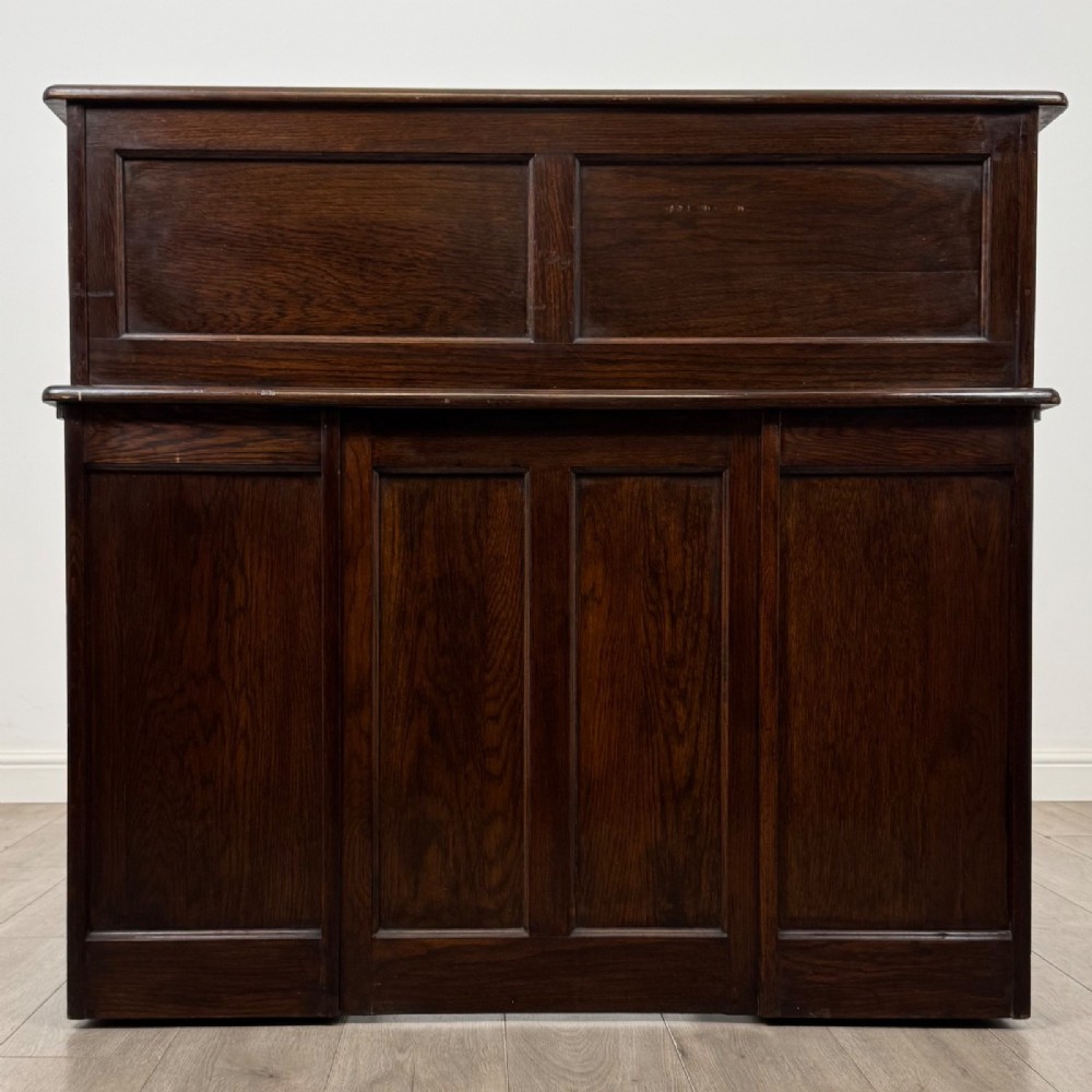An Edwardian dark oak roll top desk featuring a slatted tambour front above a twin pedestal base with eight drawers. View VI