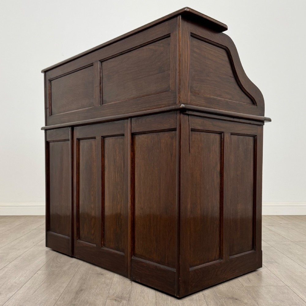 An Edwardian dark oak roll top desk featuring a slatted tambour front above a twin pedestal base with eight drawers. View VII