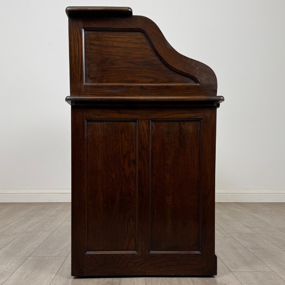 An Edwardian dark oak roll top desk featuring a slatted tambour front above a twin pedestal base with eight drawers. View VIII