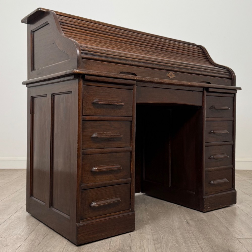 An Edwardian dark oak roll top desk featuring a slatted tambour front above a twin pedestal base with eight drawers. View IX