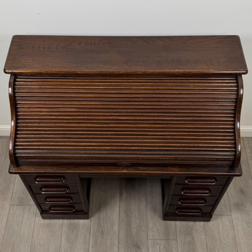 An Edwardian dark oak roll top desk featuring a slatted tambour front above a twin pedestal base with eight drawers. View X