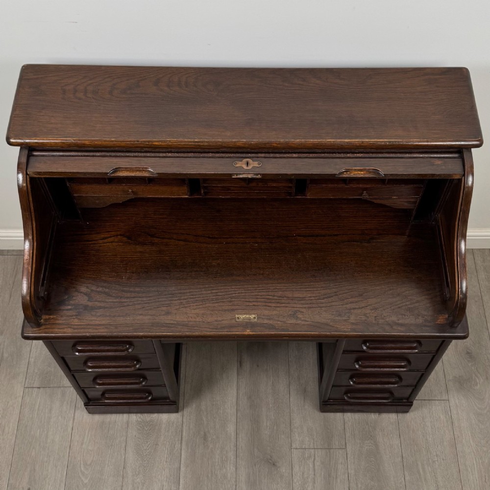 An Edwardian dark oak roll top desk featuring a slatted tambour front above a twin pedestal base with eight drawers. View XI