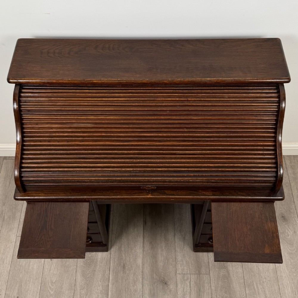 An Edwardian dark oak roll top desk featuring a slatted tambour front above a twin pedestal base with eight drawers. View XII