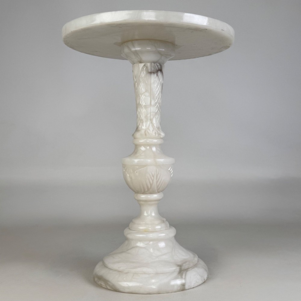 A carved white alabaster side table featuring a circular top resting on a decorative turned pedestal stem and round base. View III