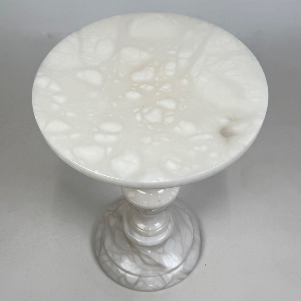 A carved white alabaster side table featuring a circular top resting on a decorative turned pedestal stem and round base. View IV