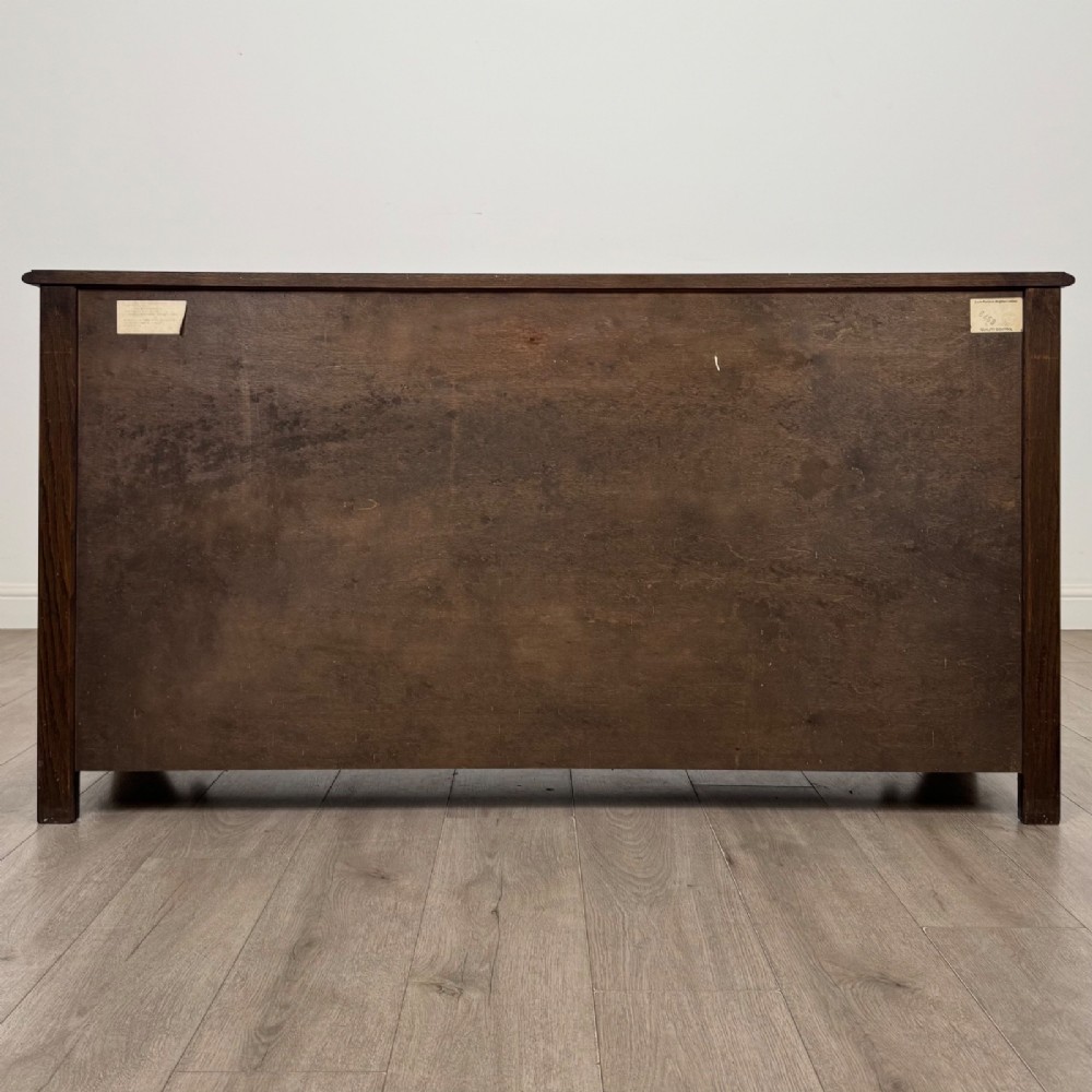 A dark oak sideboard featuring carved linenfold central doors flanked by eight drawers with metal drop ring handles. View VI