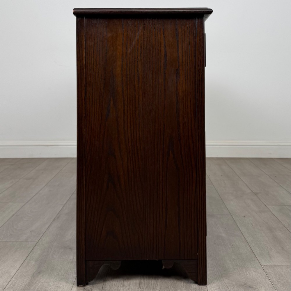 A dark oak sideboard featuring carved linenfold central doors flanked by eight drawers with metal drop ring handles. View VIII