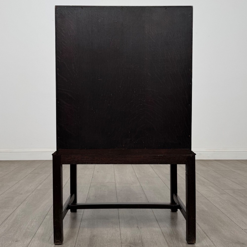 A small Edwardian dark oak writing bureau on a tall stand with two drawers featuring carved central panels and turned knobs. View VI