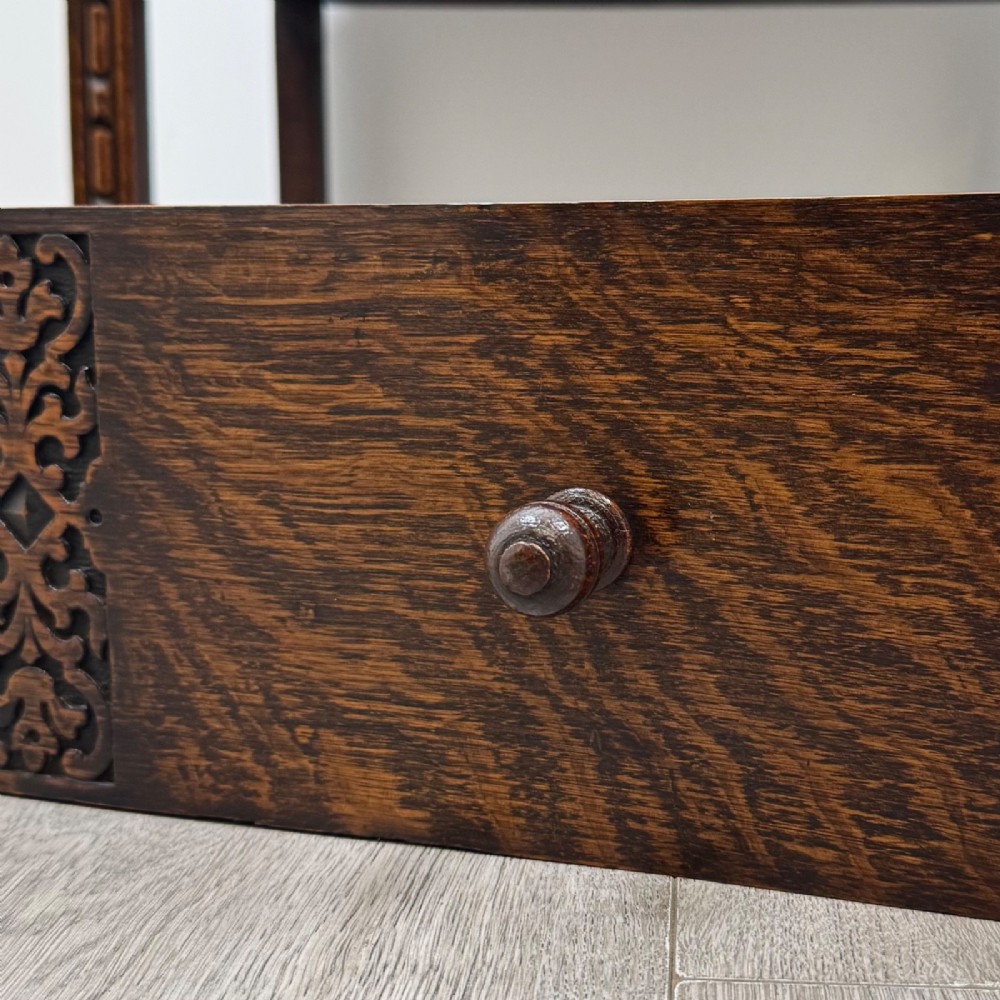A small Edwardian dark oak writing bureau on a tall stand with two drawers featuring carved central panels and turned knobs. View XIII