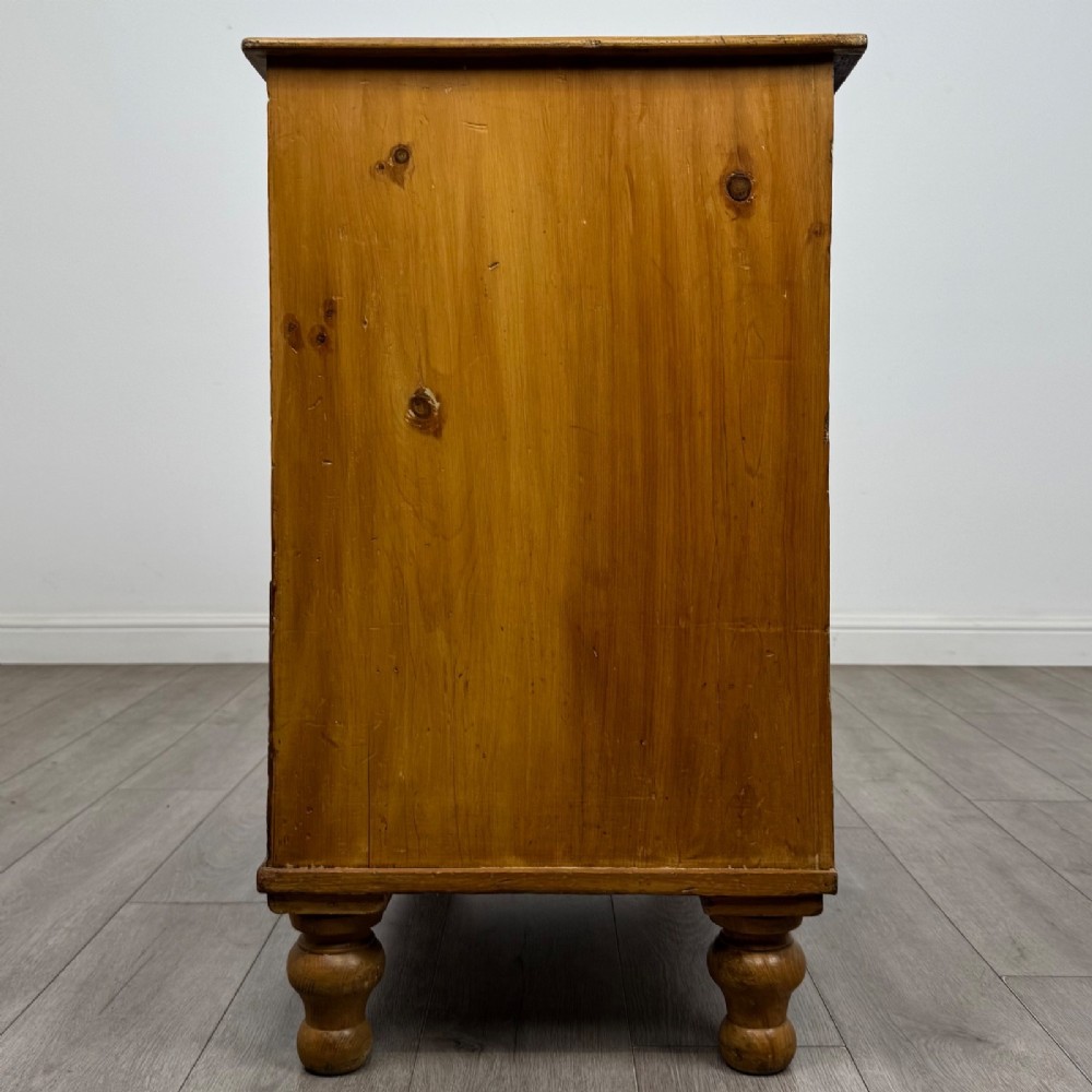 A Victorian pine chest of drawers featuring a two over two drawer layout, turned wooden knobs, and turned feet. View III