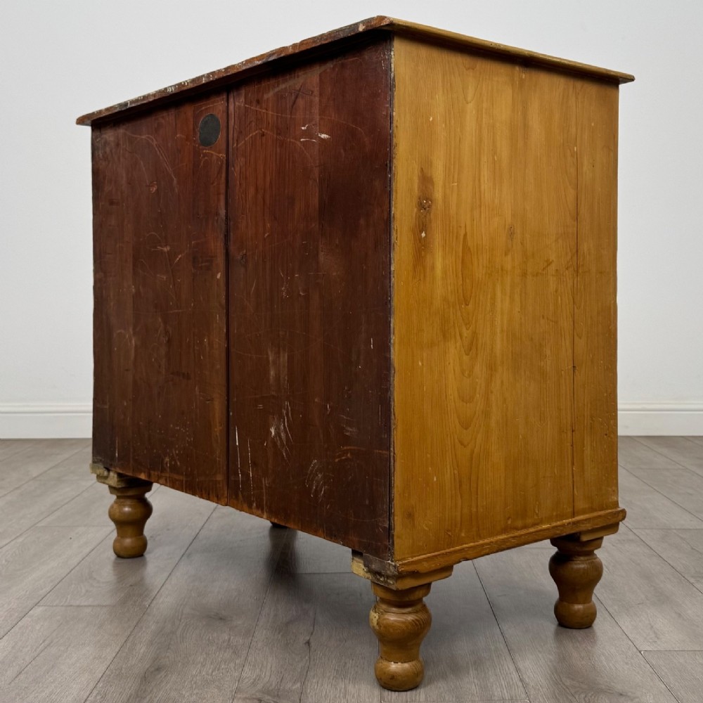A Victorian pine chest of drawers featuring a two over two drawer layout, turned wooden knobs, and turned feet. View VI
