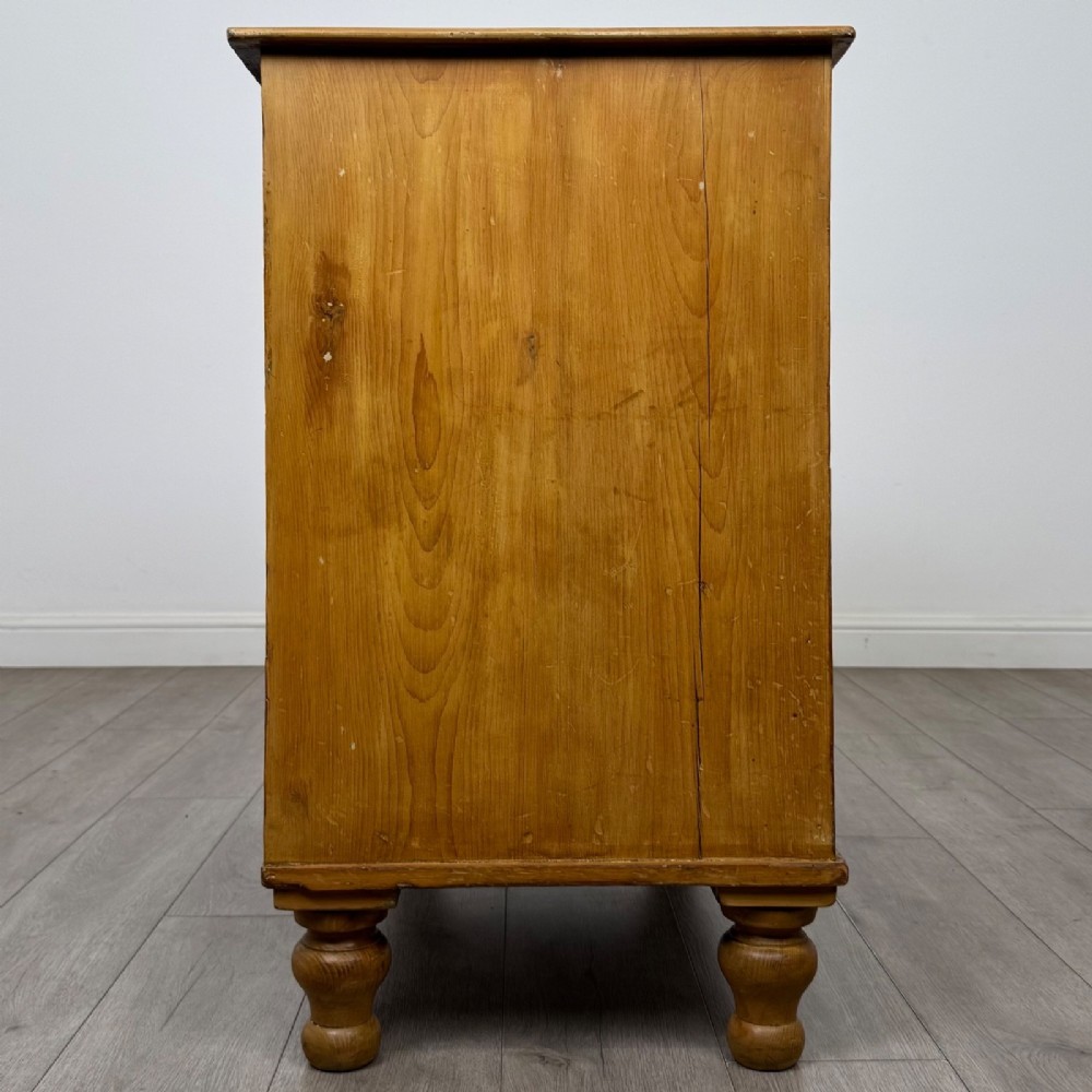 A Victorian pine chest of drawers featuring a two over two drawer layout, turned wooden knobs, and turned feet. View VII