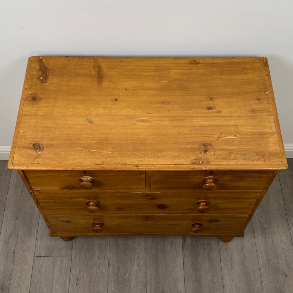 A Victorian pine chest of drawers featuring a two over two drawer layout, turned wooden knobs, and turned feet. View IX