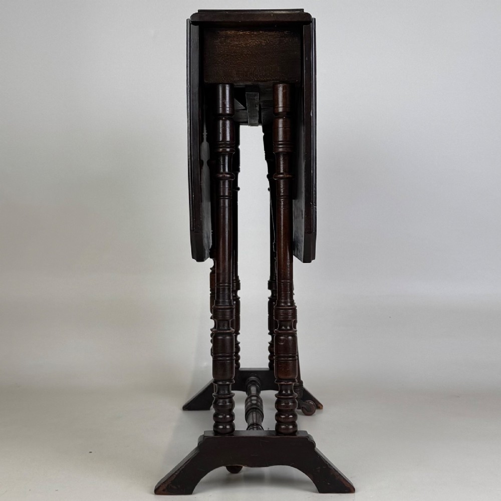 A twentieth-century dark mahogany drop-leaf table featuring turned legs, a central stretcher rail, and folding side flaps. View IV