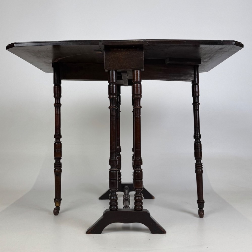 A twentieth-century dark mahogany drop-leaf table featuring turned legs, a central stretcher rail, and folding side flaps. View V