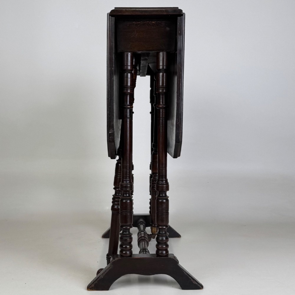 A twentieth-century dark mahogany drop-leaf table featuring turned legs, a central stretcher rail, and folding side flaps. View IX