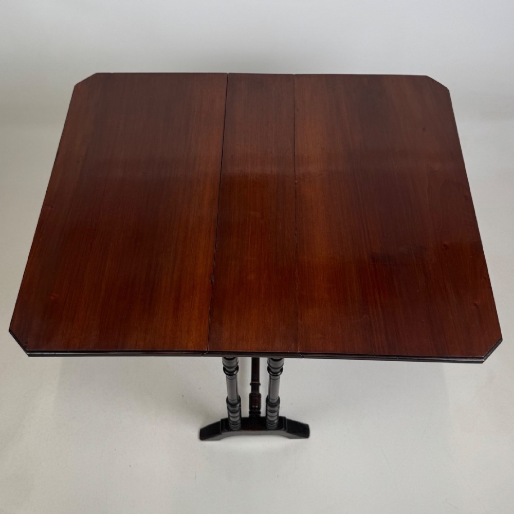 A twentieth-century dark mahogany drop-leaf table featuring turned legs, a central stretcher rail, and folding side flaps. View XI