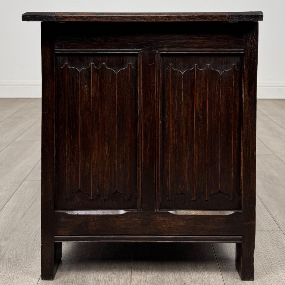 A dark oak blanket box featuring three front panels decorated with detailed Gothic arch and shield carvings. View III