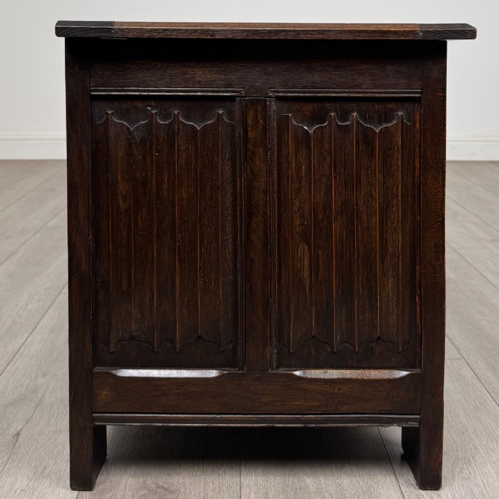 A dark oak blanket box featuring three front panels decorated with detailed Gothic arch and shield carvings. View VII