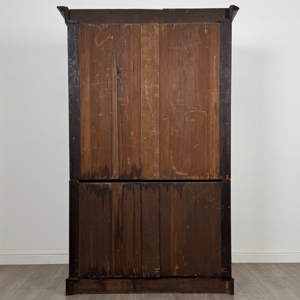 A tall 19th-century dark mahogany linen press featuring carved panelled doors on top and a chest of four drawers at the base. View VI