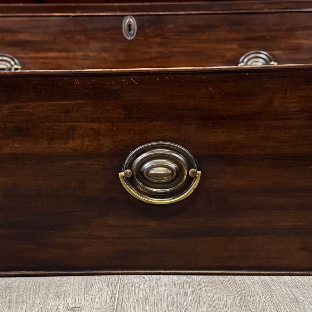 A tall 19th-century dark mahogany linen press featuring carved panelled doors on top and a chest of four drawers at the base. View XI