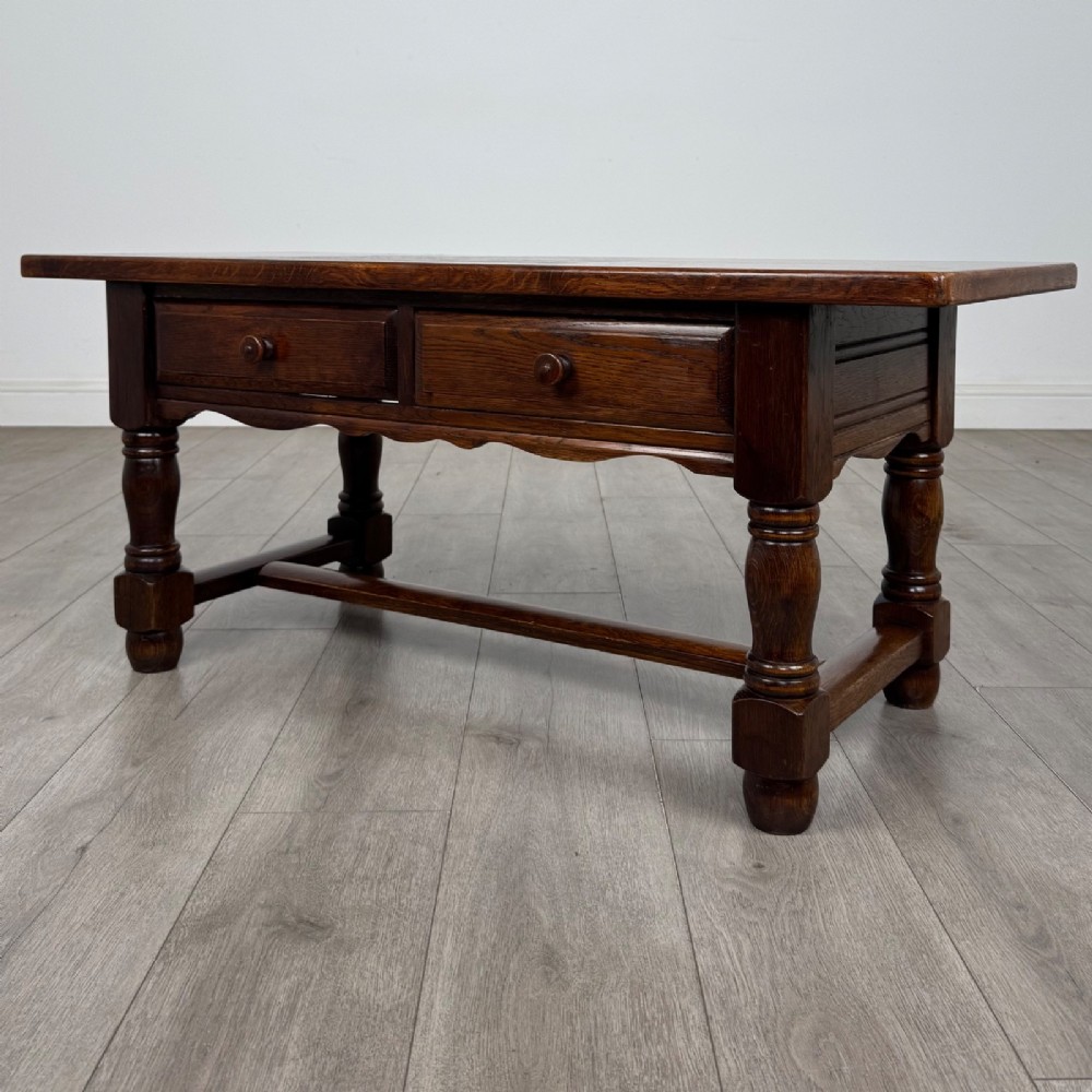 A dark oak rectangular coffee table featuring two front drawers with wooden knob handles and turned baluster legs connected by a low stretcher. View II